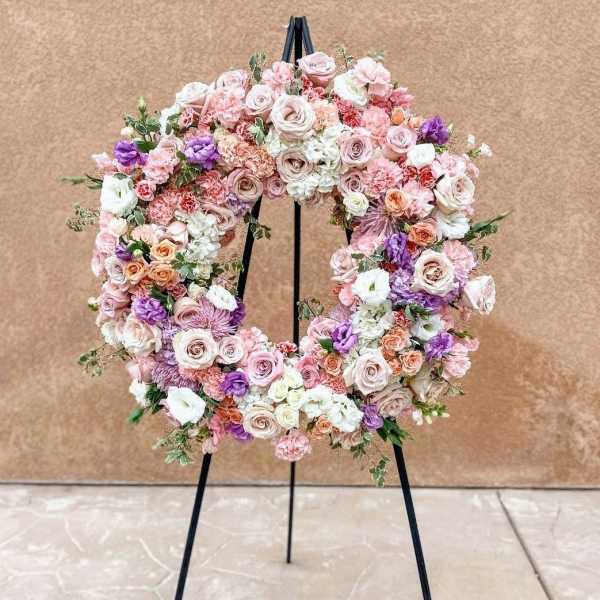 Pastel floral wreath on a black stand