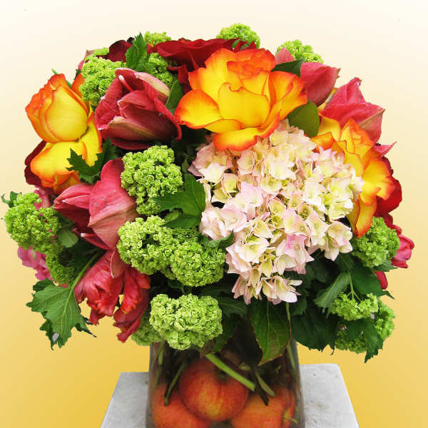 Bouquet of multicolored roses, hydrangea, and green viburnum in a glass vase