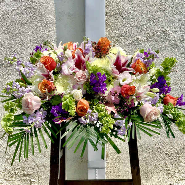 Large mixed floral arrangement with roses, lilies, and purple accents