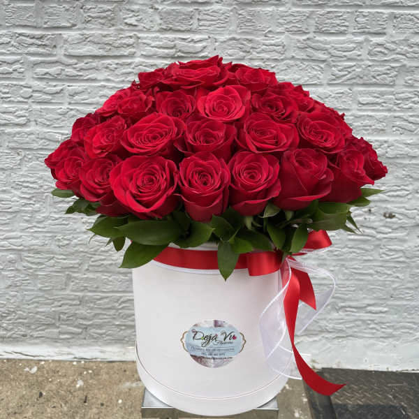 Red roses arranged in a white hat box with a red ribbon