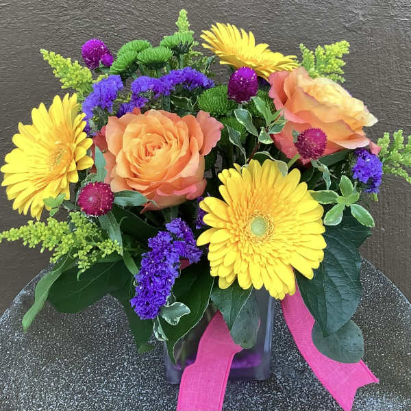 Bouquet of orange roses and yellow gerbera daisies in a glass vase