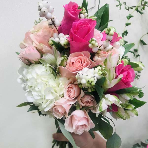 Handheld bouquet of pink and white roses with white berries