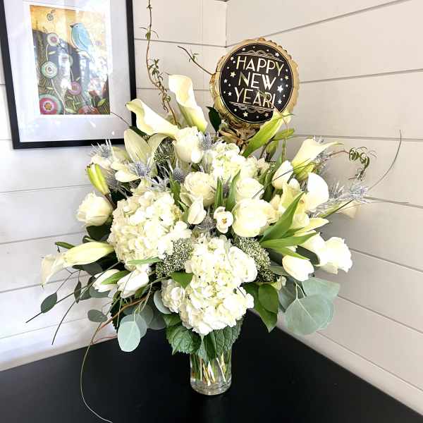 White floral arrangement in a glass vase with a Happy New Year balloon