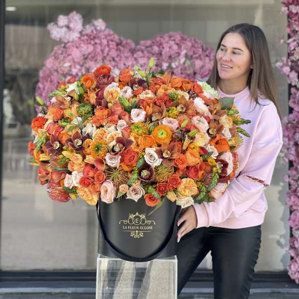 Woman holding a large mixed bouquet in a black hatbox