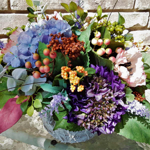 Colorful floral arrangement with blue, purple, and pink blooms in a low container