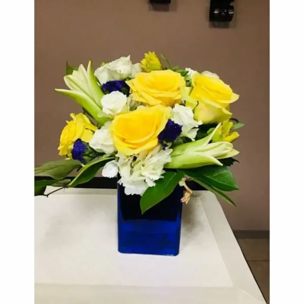 Yellow and white flower arrangement in a blue glass vase