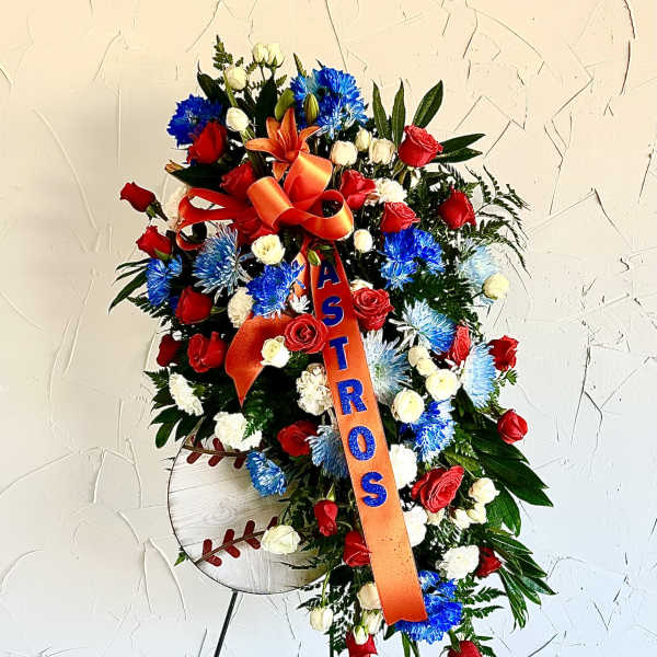 Tall standing spray of red, blue, and white flowers with orange ASTROS ribbon and baseball sign on an easel