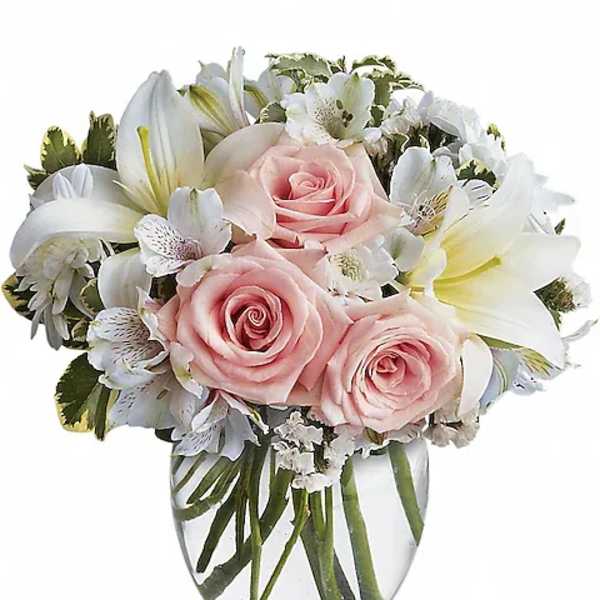 Compact bouquet of pale pink roses and white lilies in a clear glass vase