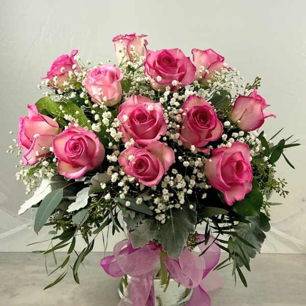 Pink roses arranged in a glass vase with baby's breath