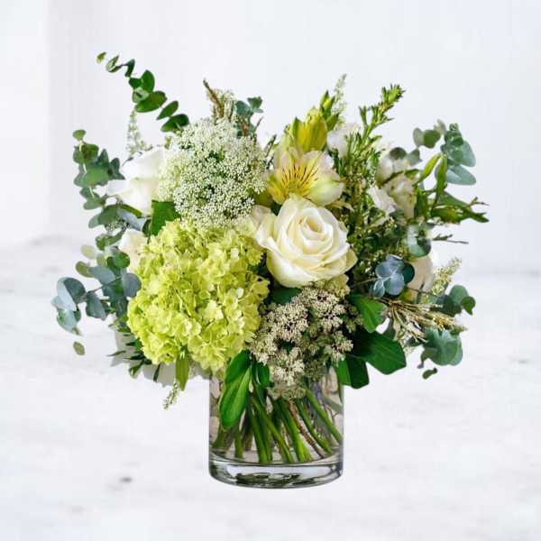 White and green floral arrangement in a clear glass vase