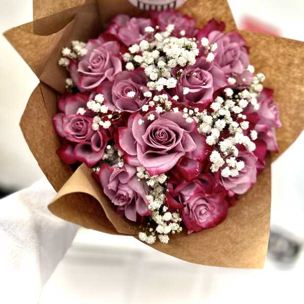 Bouquet of pink roses and white baby's breath wrapped in brown paper