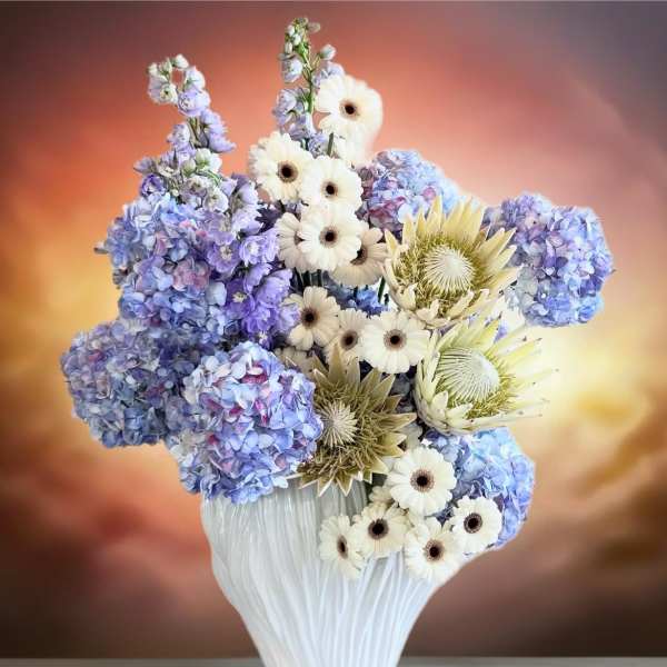 Blue hydrangeas and white daisies in a white vase