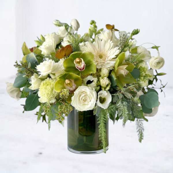 White and green mixed flower arrangement with orchids and roses in a clear glass cylinder vase