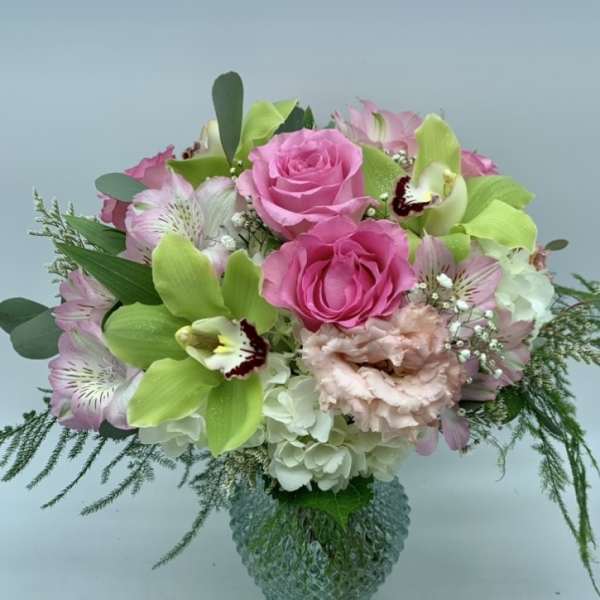 Pink roses and green orchids in a glass vase