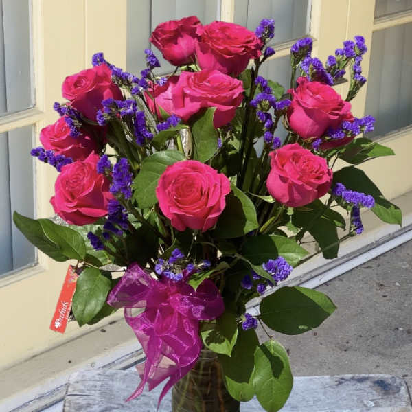 Bouquet of hot pink roses with purple filler in a glass vase