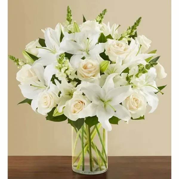 White lilies and roses arranged in a clear glass vase