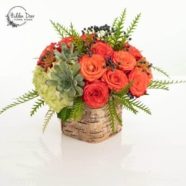 Orange roses and succulents in a birch container