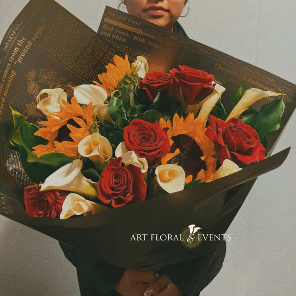 Bouquet of red roses, white calla lilies, and orange flowers wrapped in black paper