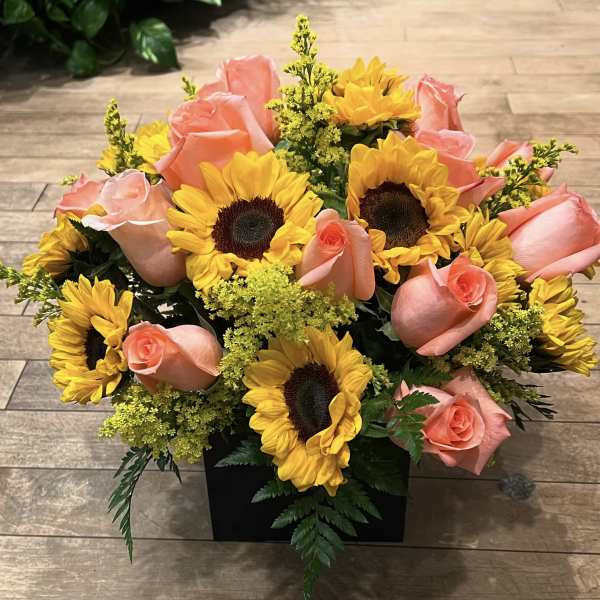 Bouquet of pink roses and yellow sunflowers in a black container