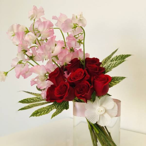 Red roses and pink sweet peas in a clear glass vase