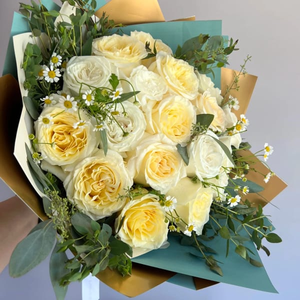 Bouquet of cream and pale yellow roses with small white daisies