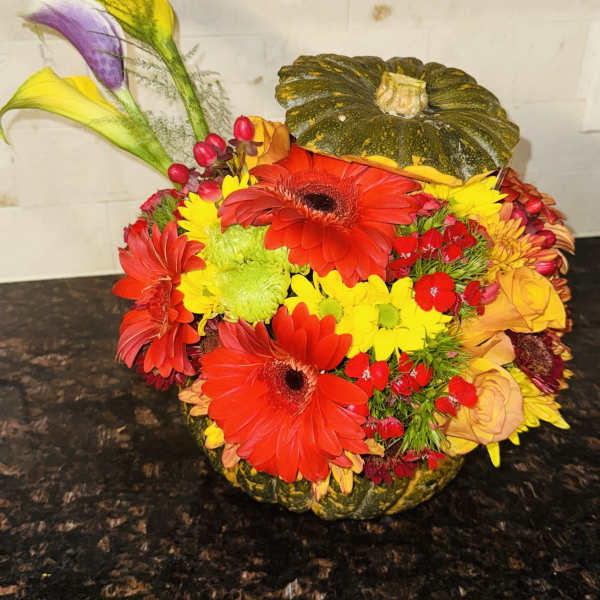 Colorful floral arrangement in a pumpkin-shaped container with calla lilies and gerberas