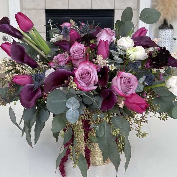 Bouquet of pink roses and dark purple calla lilies in a gold vase