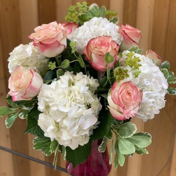 Pink-edged roses and white hydrangeas in a glass vase