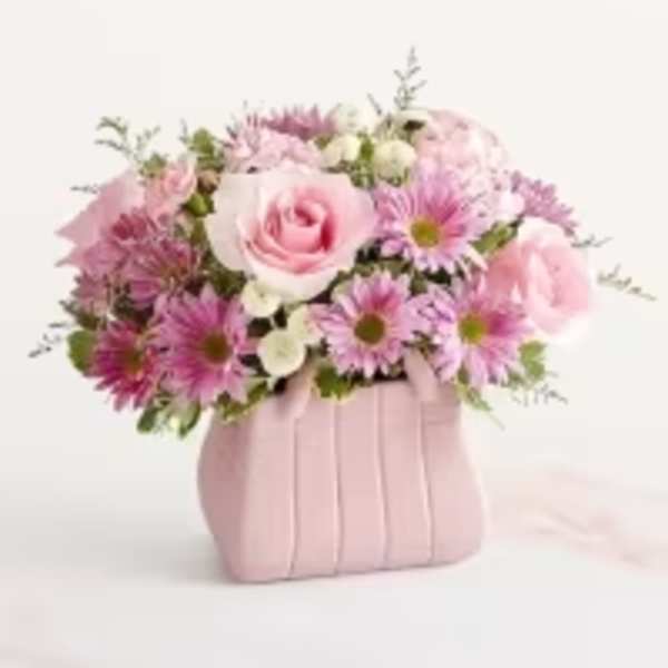 Pink roses and daisy poms arranged in a pink purse-shaped ceramic container