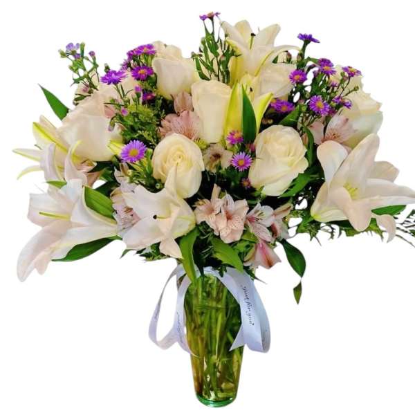 White lilies and roses with purple daisies in a glass vase
