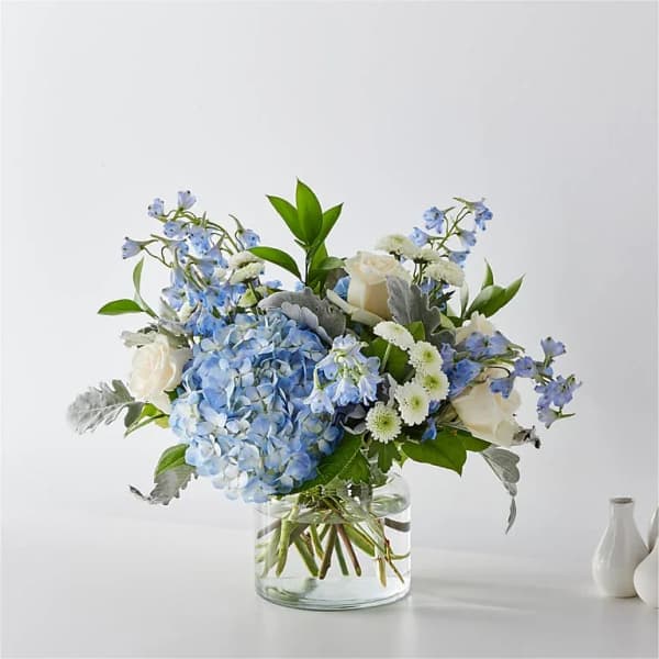 Blue hydrangea and white rose bouquet in a clear glass vase