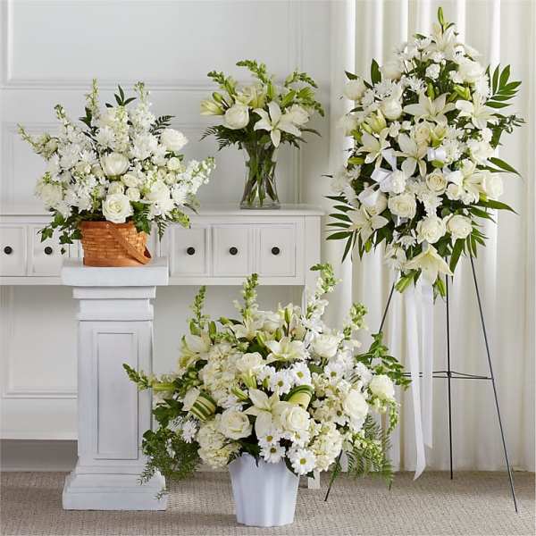 White floral arrangements with lilies and roses in vases and a basket