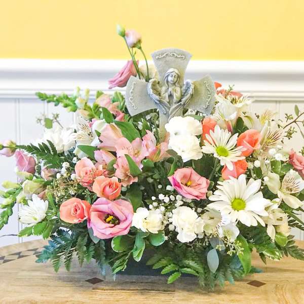 Pastel floral arrangement with a small angel figurine centerpiece