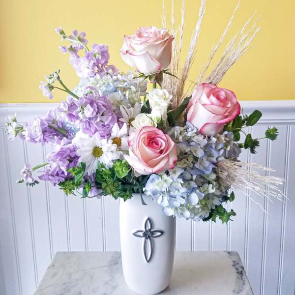 Pink roses and lavender flowers in a white vase