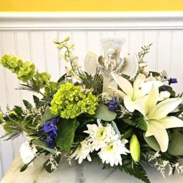 White lilies and daisies arranged around a religious figurine