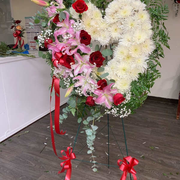 Heart-shaped floral standing spray with red roses, pink lilies, and white chrysanthemums