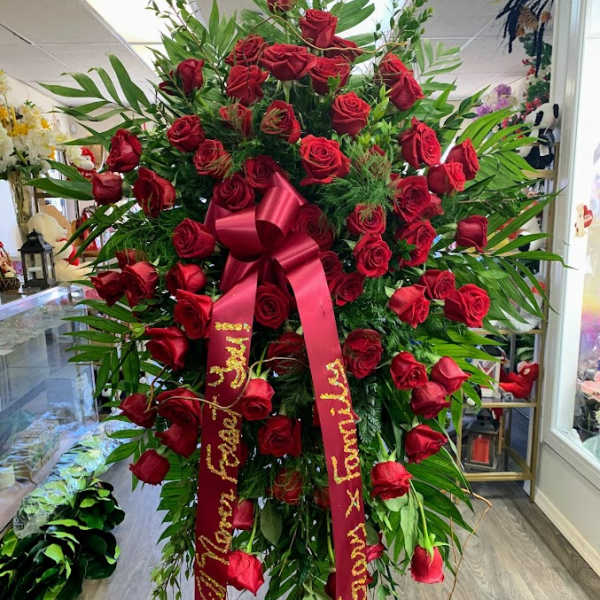 Large standing spray of red roses with a red ribbon