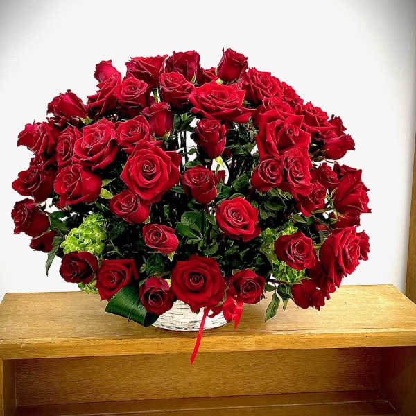 Large bouquet of red roses in a white basket with a red ribbon
