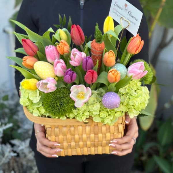 Wicker basket filled with colorful tulips, green hydrangeas, and pastel decorative eggs.
