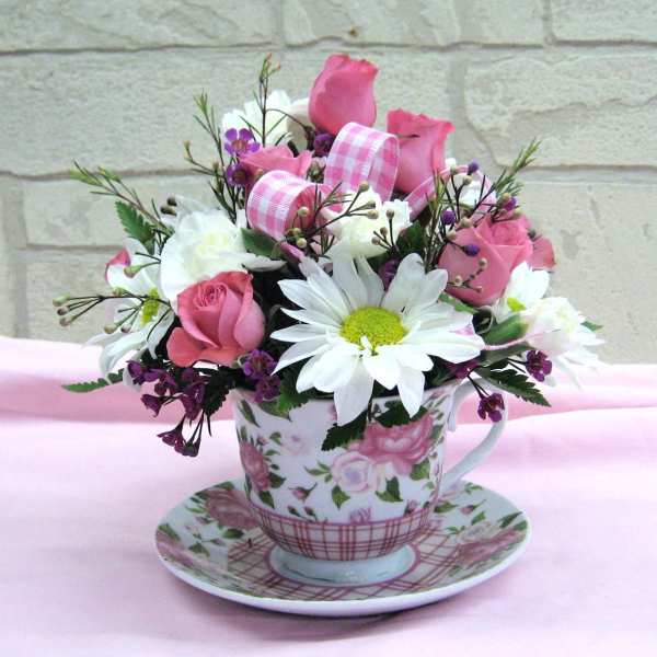 Pink and white flower arrangement in a floral teacup and saucer