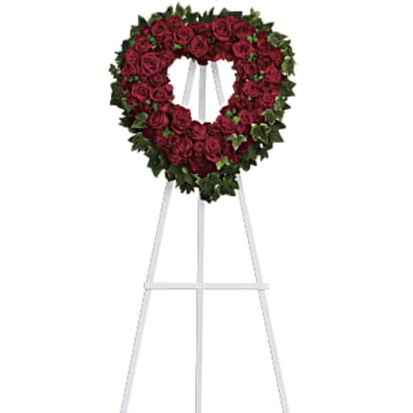 Heart-shaped red rose wreath on a white easel stand