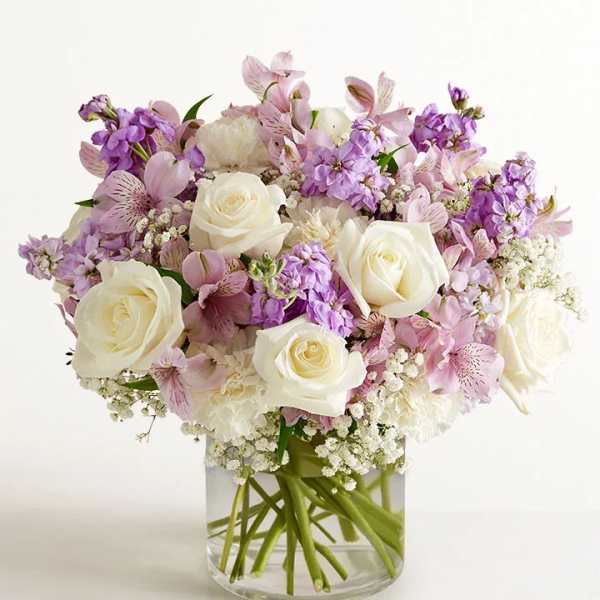 Bouquet of white roses and pink-purple flowers in a clear glass vase