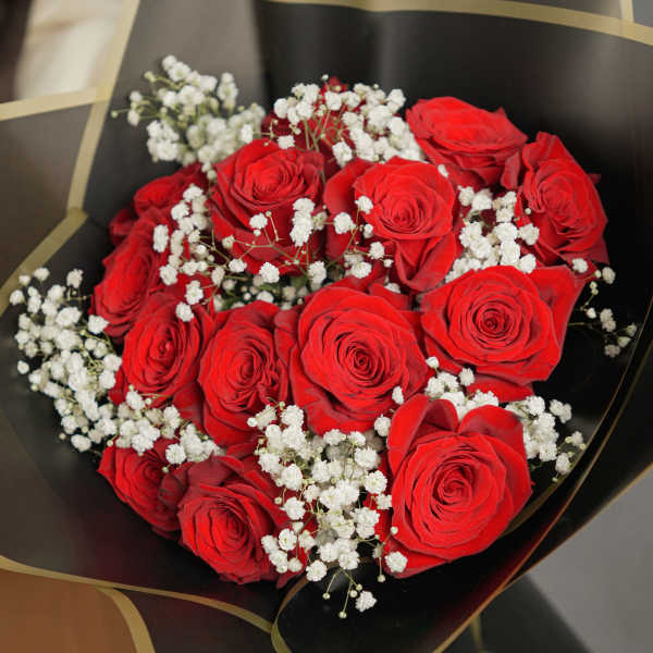Bouquet of red roses with white baby's breath in black wrap