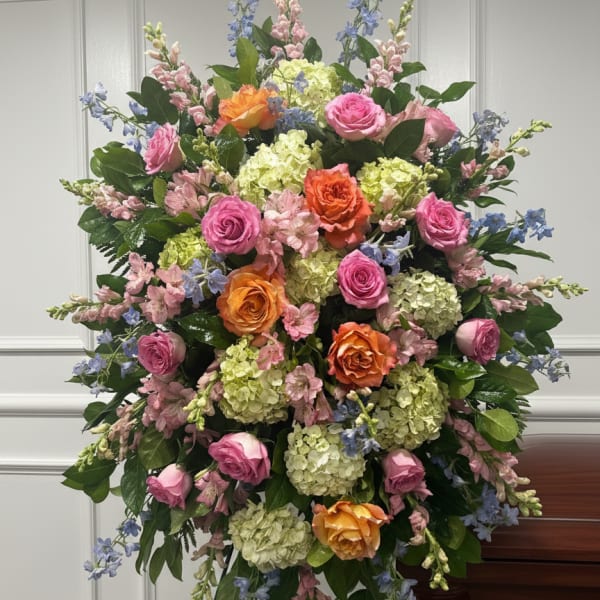 Large standing floral spray with pink, orange, and blue flowers