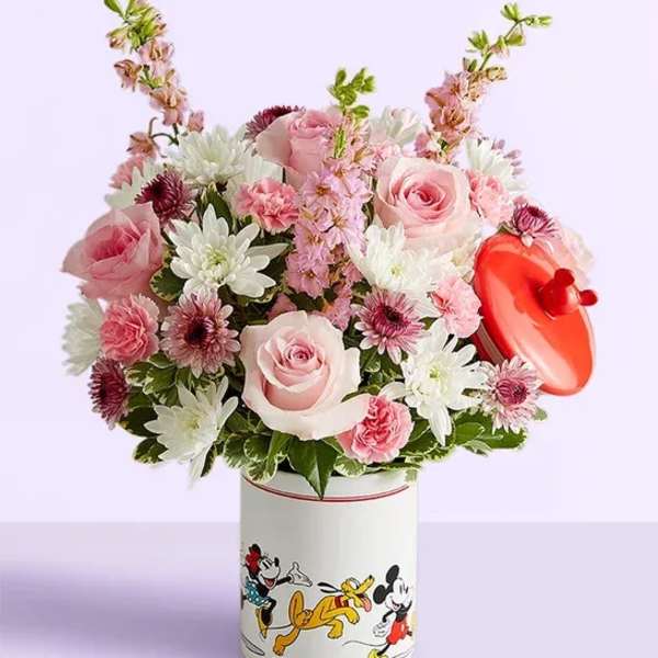 Pink and white flower arrangement in a Mickey Mouse tin with a red heart topper