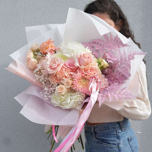 Large pastel bouquet of pink and white flowers wrapped in paper