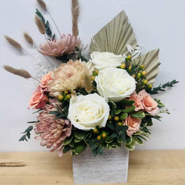 Bouquet of white and blush flowers in a square vase with dried grasses