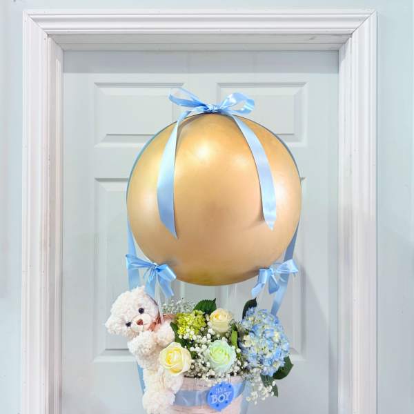 Baby gift basket with flowers, teddy bear, and gold balloon