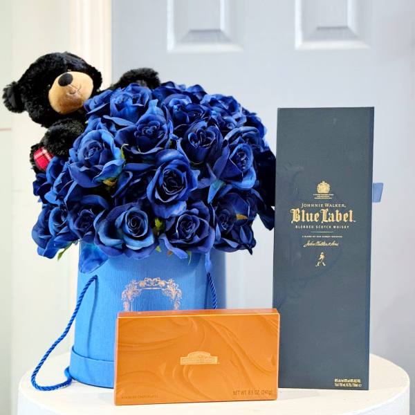 Blue rose bouquet in a gift box with a teddy bear, whiskey box, and chocolates