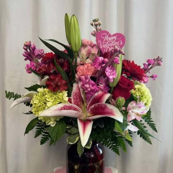 Mixed bouquet with lilies, roses, and pink flowers in a dark vase